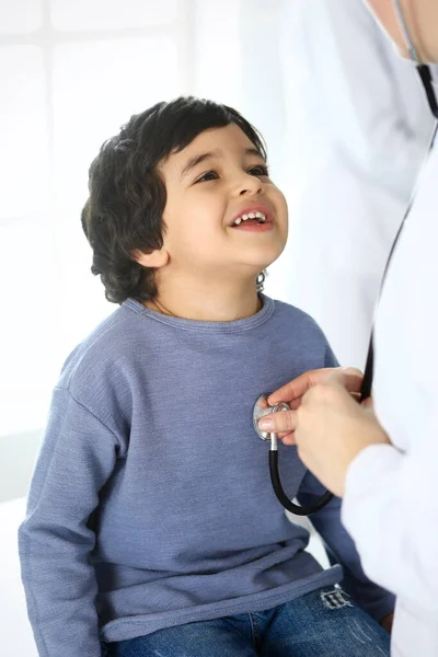 Médico examinando a un niño paciente por estetoscopio. Lindo chico árabe en la cita con el médico. Concepto de medicina y salud — Foto de Stock