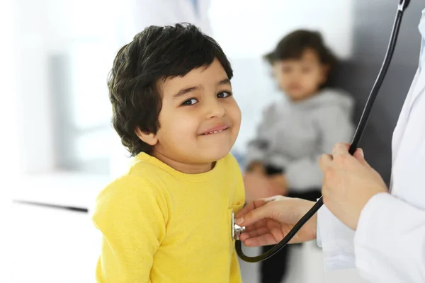 Лікар, який вивчає пацієнта за стетоскопом. Милий арабський хлопчик за призначенням лікаря. Медицина та концепція охорони здоров'я — стокове фото
