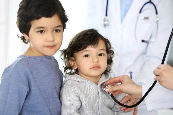 Arzt untersucht eine Kinderpatientin mit einem Stethoskop. Netter arabischer Junge beim Arzttermin. Medizin und Gesundheitskonzept — Stockfoto