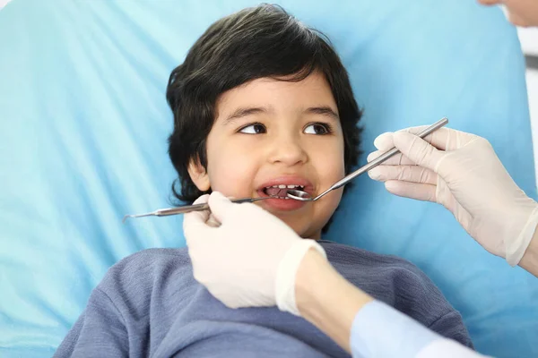 Mały arabski chłopiec siedzący na krześle dentystycznym z otwartymi ustami podczas kontroli doustnej, podczas gdy lekarz. Odwiedzam gabinet dentystyczny. Koncepcja medycyny i stomatologii — Zdjęcie stockowe