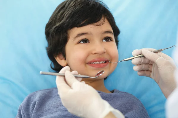 Mały arabski chłopiec siedzący na krześle dentystycznym z otwartymi ustami podczas kontroli doustnej, podczas gdy lekarz. Odwiedzam gabinet dentystyczny. Koncepcja medycyny i stomatologii — Zdjęcie stockowe