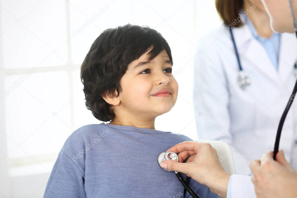 Doctor examining a child patient by stethoscope. Cute arab boy at physician appointment. Medicine and healthcare concept