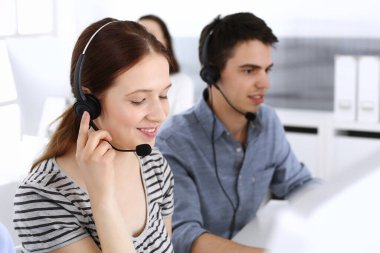 Bir grup operatör iş başında. Merkezi ara. Müşteri hizmetlerinde çalışan güzel kadın resepsiyonistlere odaklan. İş konsepti ve günlük çizgili giyim tarzı