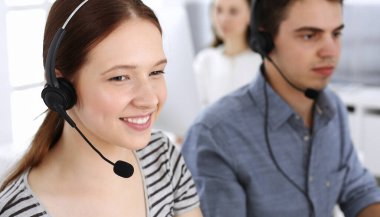 Bir grup operatör iş başında. Merkezi ara. Müşteri hizmetlerinde çalışan güzel kadın resepsiyonistlere odaklan. İş konsepti ve günlük çizgili giyim tarzı