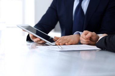 Modern ofiste birlikte çalışırken iş adamları tablet bilgisayar kullanıyorlar. İş yerinde iş arkadaşı olan tanınmamış bir iş adamı ya da erkek girişimci. Takım çalışması ve ortaklık kavramı