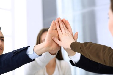 Takım çalışması yapan ve el ele tutuşan iş adamları grubu ya da modern ofiste kontrat imzaladıktan sonra beş kişi. Meslektaşları ya da avukatları olan tanınmamış işadamı ve kadın elleriyle daire çiziyor.