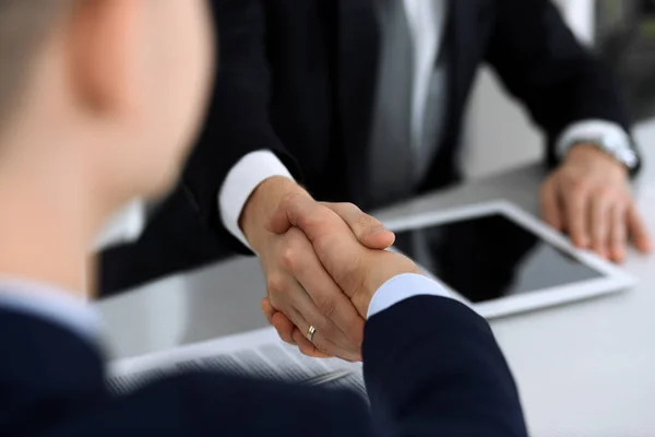 Zakenmensen schudden elkaar de hand na het tekenen van het contract aan het glazen bureau in het moderne kantoor. Onbekende zakenman, mannelijke ondernemer met collega 's bij ontmoeting of onderhandeling. Teamwork, partnerschap en — Stockfoto