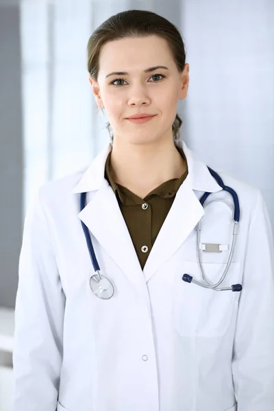 Doctora mujer feliz y alegre mientras está de pie en la oficina del hospital. Servicio médico perfecto en la clínica. Concepto de medicina y salud — Foto de Stock