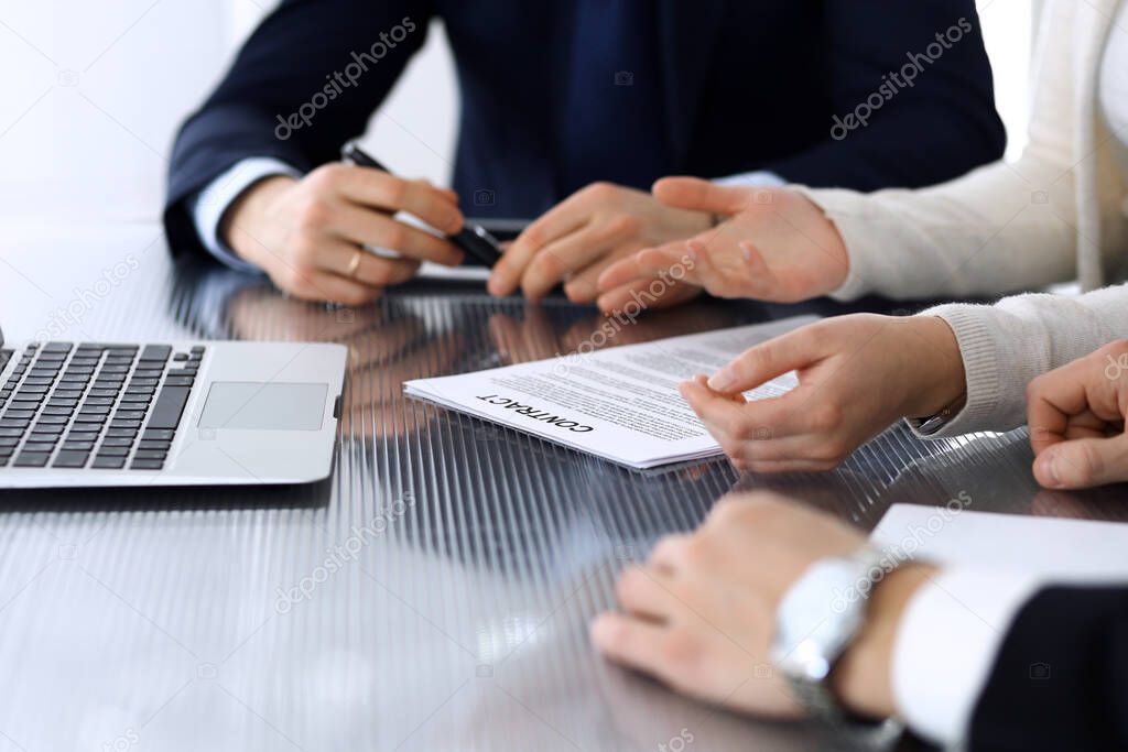 Business people discussing contract working together at meeting at the glass desk in modern office. Unknown businessman and woman with colleagues or lawyers at negotiation. Teamwork and partnership
