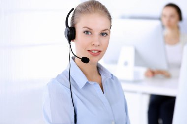 Merkezi ara. İnternette müşterilere danışmak için bilgisayar ve kulaklık kullanan güzel sarışın kadın. Müşteri hizmetleri işgali olarak çalışan bir grup operatör. İş adamları konsepti