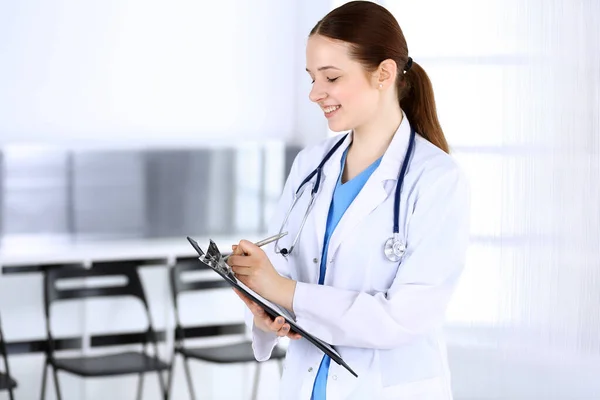 Doktorand eller praktikant på jobbet. Läkare fylla upp medicinhistoria rekord när du står på akutmottagningen. Medicin och hälsovård — Stockfoto