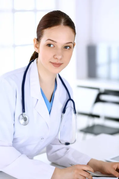 Doctora en el trabajo. Médico o estudiante interno llenando documentos médicos o prescripción mientras está de pie en la recepción del hospital. Datos en medicina y concepto de salud — Foto de Stock