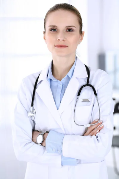 Dottoressa donna colpita alla testa al lavoro in ospedale. Medico in piedi dritto e sorridente, ritratto in studio. Medicina e concetto di assistenza sanitaria — Foto Stock