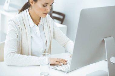 Ofiste bilgisayarla çalışan sıradan giyinmiş bir iş kadını. İş yerinde avukat ya da muhasebeci