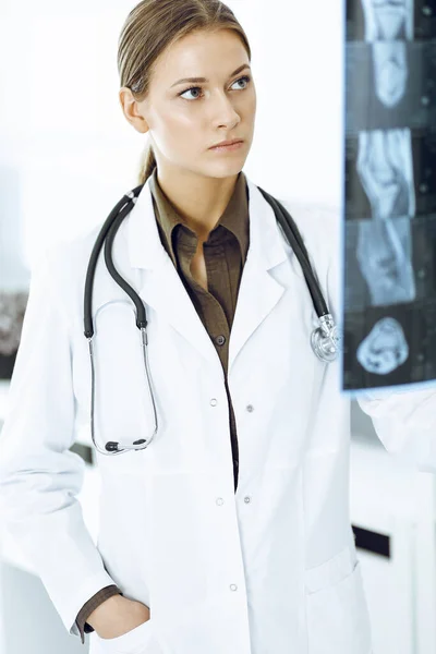 Woman-doctor examining x-ray picture in hospital. Orthopedist at work in clinic. Medicine and healthcare concept — Stock Photo, Image