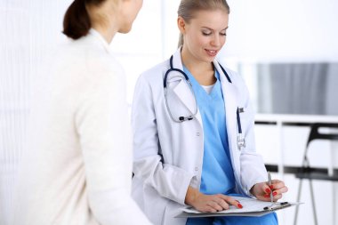 Muayene sırasında doktor ve hasta. Acil serviste portre çekimi yaparken ilaç geçmişini dolduran bir doktor. İlaç ve sağlık hizmetleri kavramı