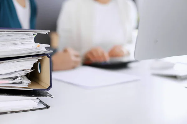 Bnders with papers are waiting to be processed by business woman or bookkeeper working at the desk in office back in blur. Internal Tax and Audit concept — Stock Photo, Image