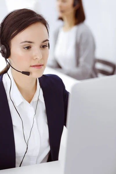 Centro de llamadas. Hermosa mujer sentada y trabajando en auriculares en la oficina de servicio al cliente. Concepto empresarial —  Fotos de Stock