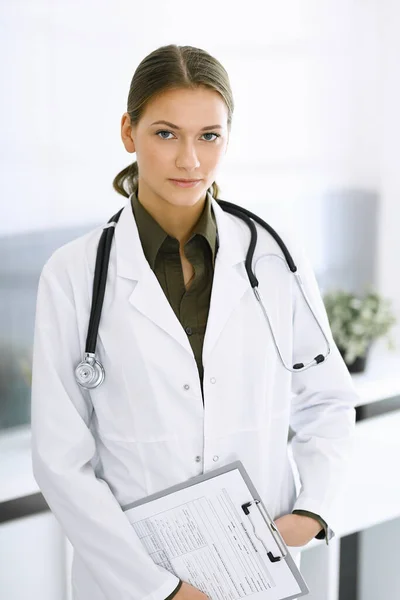 Γυναίκα-γιατρός στέκεται και κοιτάζει την κάμερα. Τέλεια ιατρική υπηρεσία στην κλινική. Ιατρική και υγειονομική περίθαλψη — Φωτογραφία Αρχείου