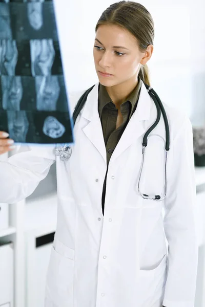 Mulher-médico examinando imagem de raio-X no hospital. Cirurgião ou ortopedista no trabalho na clínica. Conceito de medicina e saúde — Fotografia de Stock