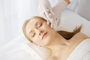 Güzellik doktoru, beyaz kadın yüzüne şırıngayla güzellik prosedürü uyguluyor. Kozmetik tıp ve cerrahi, güzellik enjeksiyonları konsepti