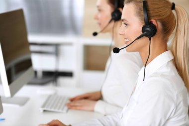 Merkezi ara. İnternette müşterilere danışırken kulaklık kullanan mutlu ve heyecanlı bir iş kadını. Müşteri hizmetleri ofisi ya da tele pazarlama bölümü. İşte gülümseyen operatörler grubu