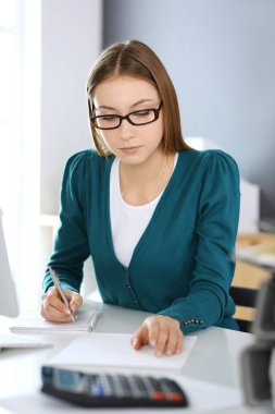 Muhasebeci mali durumu kontrol ediyor ya da vergi formları için hesap makinesi geliri ile sayıyor, eller yakın çekim. Ofisteki masada oturan ve çalışan bir iş kadını. Denetim kavramı