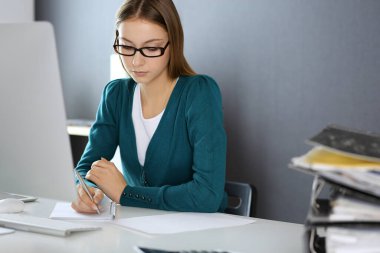 Muhasebeci mali durumu kontrol ediyor ya da vergi formları için hesap makinesi geliri ile sayıyor, eller yakın çekim. Ofisteki masada oturan ve çalışan bir iş kadını. Denetim kavramı