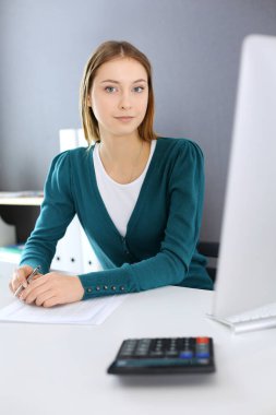 Muhasebeci mali durumu kontrol ediyor ya da vergi formları için hesap makinesi geliri ile sayıyor, eller yakın çekim. Ofisteki masada oturan ve çalışan bir iş kadını. Denetim kavramı