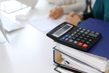 Hesap makinesi ve kağıtlar iş kadını ya da ofisteki büroda çalışan muhasebeci tarafından incelenmeyi bekliyor. İç Denetim ve vergi kavramı