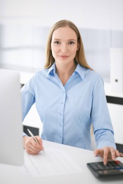 Muhasebeci mali durumu kontrol ediyor ya da hesap makinesi geliri ile vergi formunu sayıyor. Ofisteki masada oturan ve çalışan bir iş kadını. Denetim kavramı