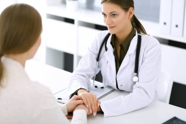 Kadın doktor hastane ofisindeki kadın hastasına güvence veriyor. Sağlık hizmetlerinde tıbbi etik, insan desteği ve güven kavramı