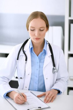 Hastane bürosundaki masada otururken ilaç kayıtlarını dolduran doktor kadın. Hekim kadın iş başında. Tıp ve sağlık alanlarındaki veriler