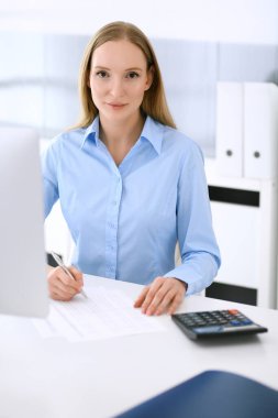 Muhasebeci mali durumu kontrol ediyor ya da hesap makinesi geliri ile vergi formunu sayıyor. Ofisteki masada oturan ve çalışan bir iş kadını. Denetim kavramı