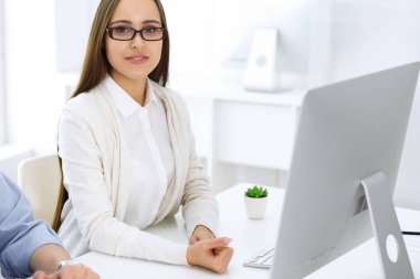 İş kadını ve erkek ofiste bilgisayar başında oturuyor ve çalışıyor. İş arkadaşları toplantıda bir şey tartışıyor. Şirket takım çalışması ve ortaklık kavramları