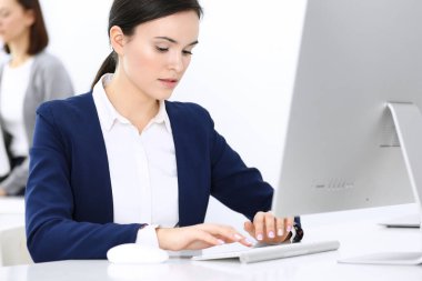 Ofiste bilgisayarla çalışan bir iş kadını, arka planda çalışan bir iş arkadaşı. Masada otururken avukatın ya da muhasebecinin vesikalığı.