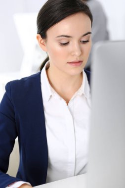 Ofiste bilgisayarla çalışan bir iş kadını, arka planda çalışan bir iş arkadaşı. Masada otururken avukatın ya da muhasebecinin vesikalığı.