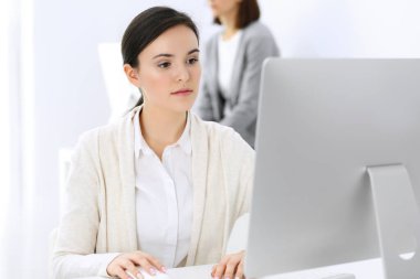 Ofiste bilgisayarla çalışan bir iş kadını, arka planda çalışan bir iş arkadaşı. Masada otururken avukatın ya da muhasebecinin vesikalığı.