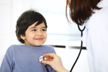 Doktor steteskopla çocuk bir hastayı muayene ediyor. Doktor randevusunda tatlı bir Arap çocuk. Tıp ve sağlık hizmetleri kavramı