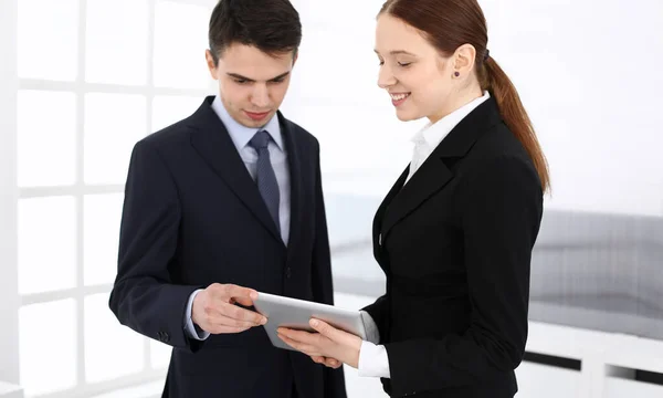Businessman and woman using tablet computer for discussing questions in office. Partners or colleagues at meeting. Business cooperation concept — Stock Photo, Image