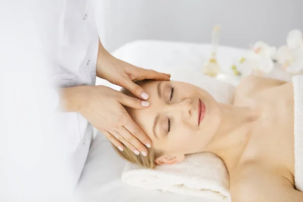 Beautiful caucasian woman enjoying facial massage with closed eyes in spa salon. Relaxing treatment in medicine and Beauty concept — Stock Photo, Image