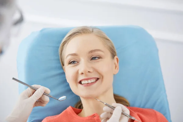 Smiling caucasian woman is being examined by dentist at dental clinic. Healthy teeth and medicine, stomatology concept — Stock Photo, Image