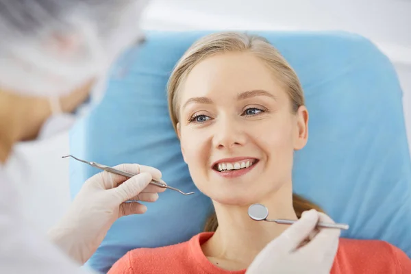Gülümseyen beyaz kadın dişçi kliniğinde dişçi tarafından muayene ediliyor. Sağlıklı dişler ve ilaçlar, stomatoloji konsepti