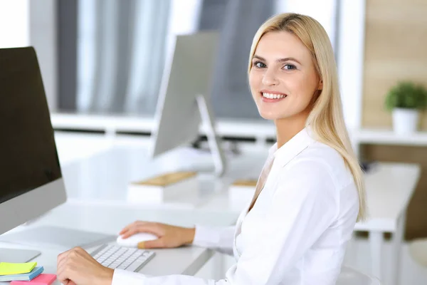 Mujer de negocios que utiliza la computadora en el lugar de trabajo en la oficina moderna. Secretaria o abogada mirando a la cámara y feliz sonriente. Trabajar por placer y éxito —  Fotos de Stock