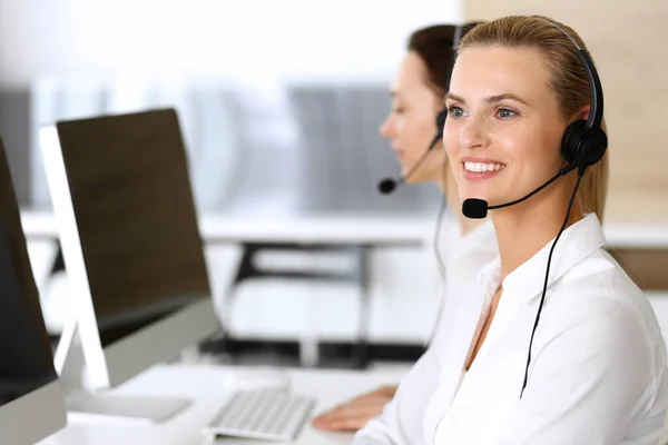 Samtalscentralen. Glad och upphetsad affärskvinna som använder headset medan du konsulterar kunder online. Kundtjänst eller telemarketing avdelning. Leende grupp av operatörer i arbete — Stockfoto
