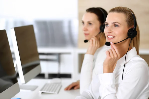 Volejte centrálu. Šťastné a vzrušené obchodní žena pomocí sluchátka při konzultaci klientů on-line. Oddělení zákaznického servisu nebo telemarketingu. Usmívající se skupina operátorů při práci — Stock fotografie