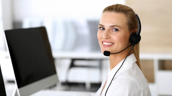 Volejte centrálu. Šťastné a vzrušené obchodní žena pomocí sluchátka při konzultaci klientů on-line. Oddělení zákaznického servisu nebo telemarketingu. Usmívající se blondýnka v práci — Stock fotografie