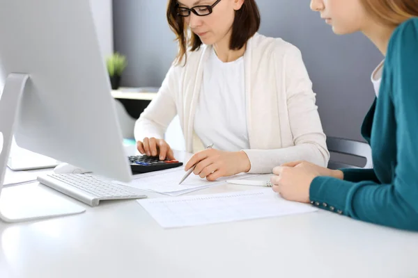 Contabilista verificando ficha financeira ou contando por calculadora de renda para a forma de imposto, mãos close-up. Mulher de negócios sentada e trabalhando com colega na mesa no escritório. Conceito de auditoria — Fotografia de Stock