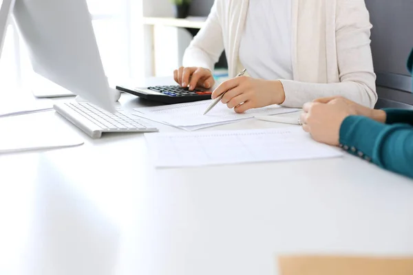 Contador que comprueba el estado financiero o cuenta por la renta de la calculadora para el formulario de impuestos, manos de cerca. Mujer de negocios sentada y trabajando con un colega en el escritorio de la oficina. Concepto de auditoría —  Fotos de Stock