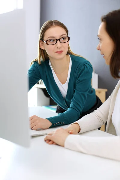 Bizneswoman daje prezentację swojej koleżance, gdy siedzi przy biurku z komputerem. Grupa ludzi biznesu pracujących w biurze. Koncepcja pracy zespołowej — Zdjęcie stockowe